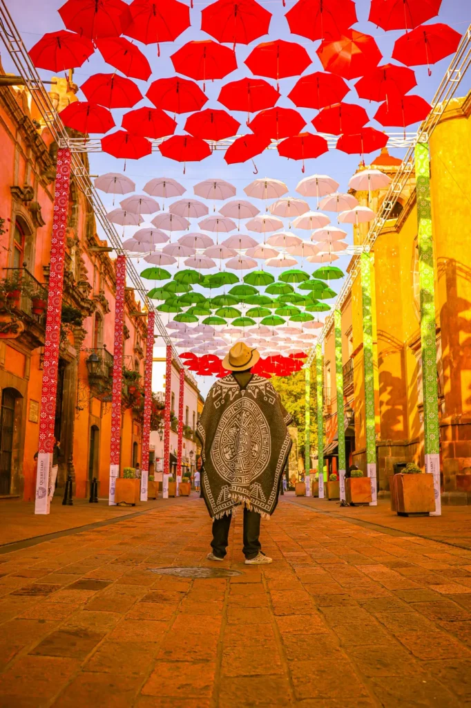 Man wearing traditional Mexican poncho walking through colourful street market – cultural heritage UK blog