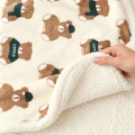 Close-up of the LittleNest Green Bear printed flannel face and white fleece reverse